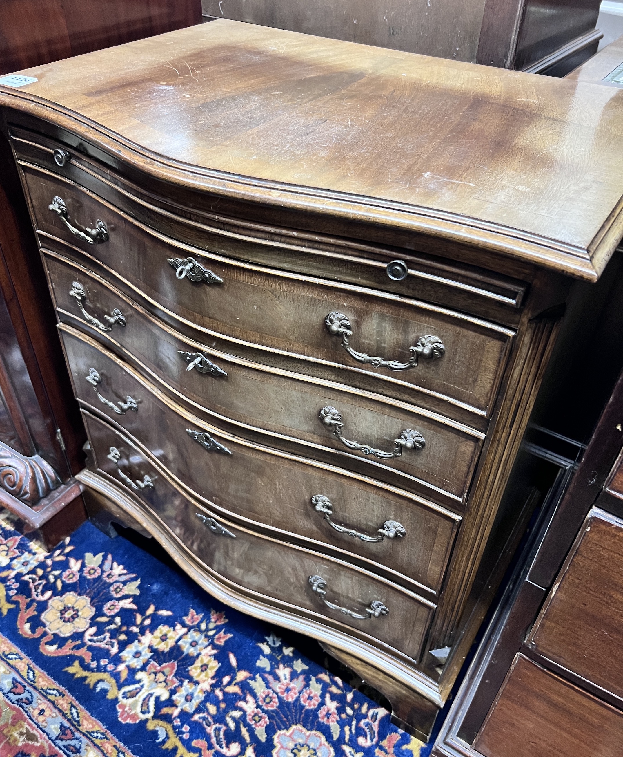 A small reproduction serpentine mahogany chest of four graduating long drawers with brushing slide, width 71cm